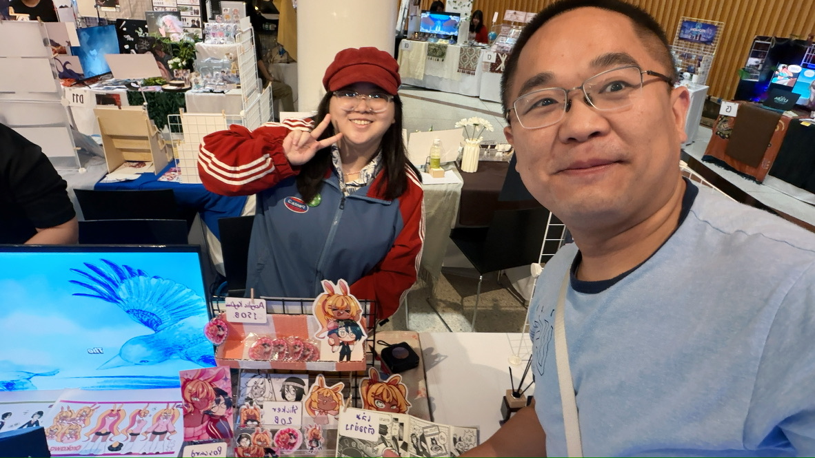 Terry taking a selfie with an artist at a booth displaying aquatic illustrations and character stickers