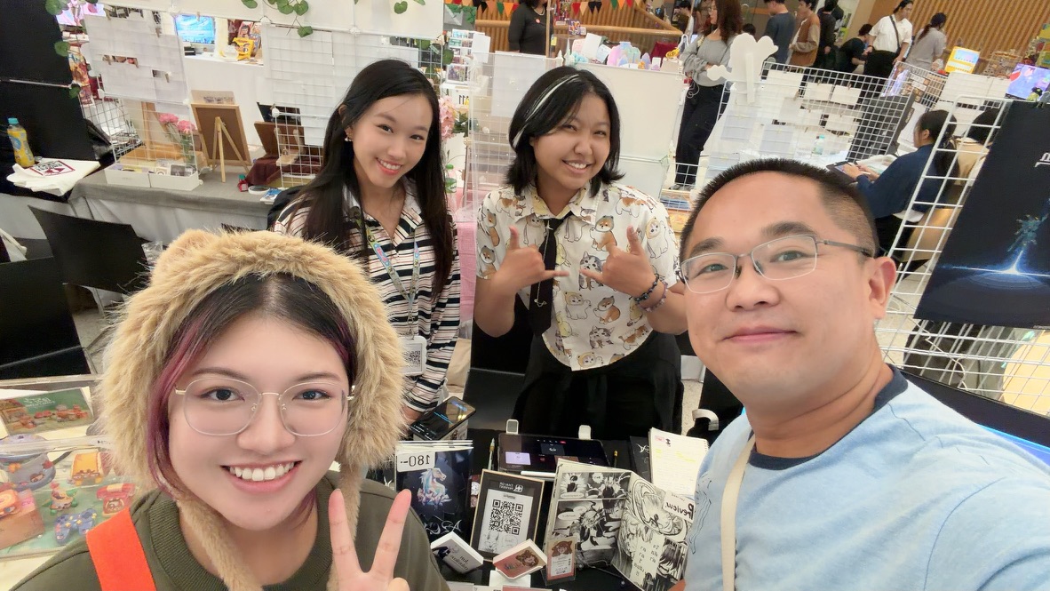 Terry taking a group selfie with three artists behind their illustration booth