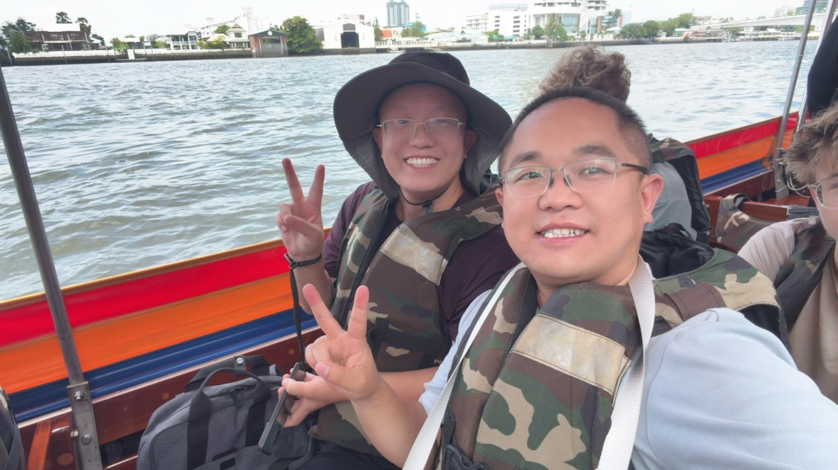 Terry and a friend wearing life jackets and smiling aboard a boat on the Chao Phraya River