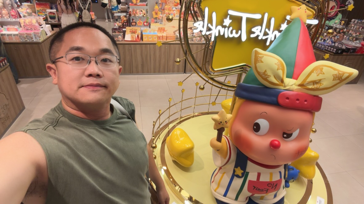 Terry taking a selfie beside a colorful character statue in a Bangkok toy store
